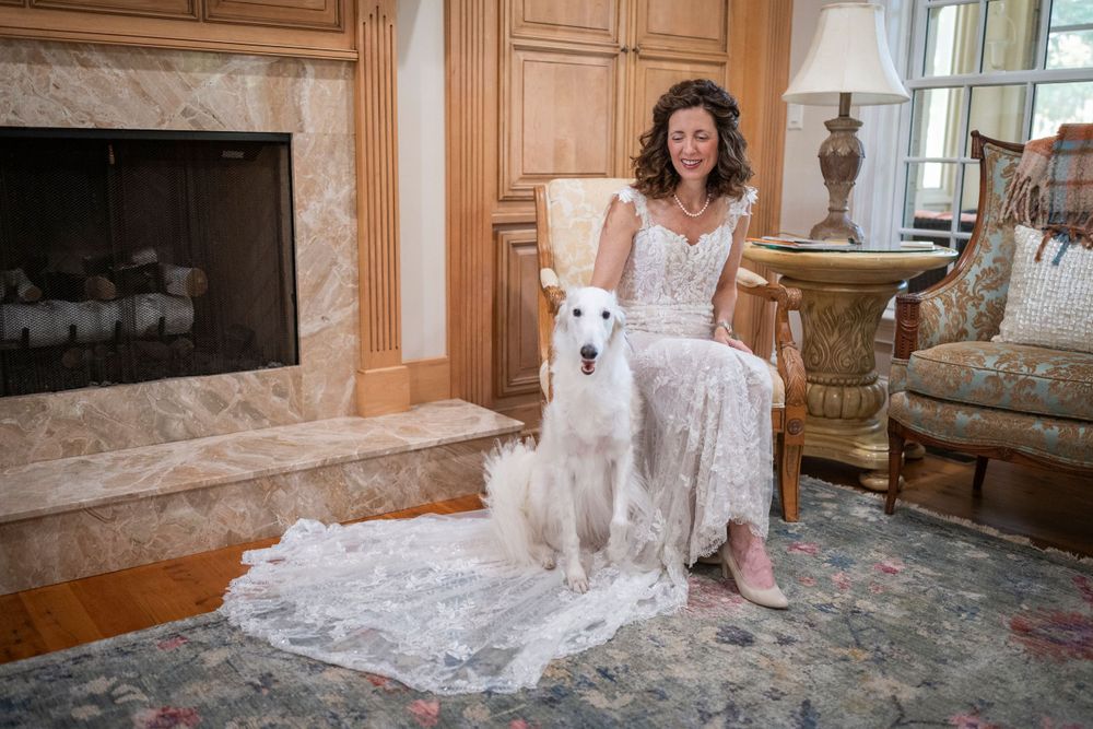 A bridal portrait with a white dog in an elegant living room with fireplace.