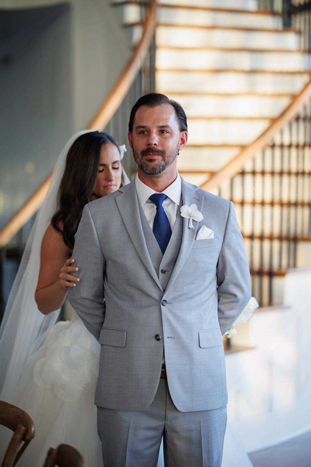 A wedding couple shares an intimate moment near an elegant staircase.
