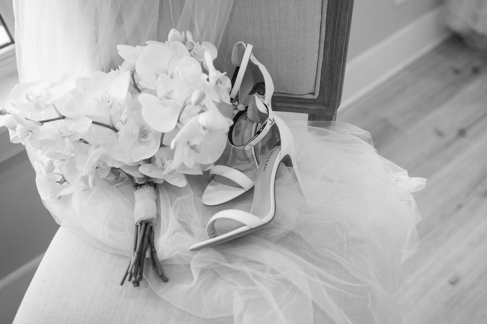Close-up details of a bride's white wedding dress and bouquet.