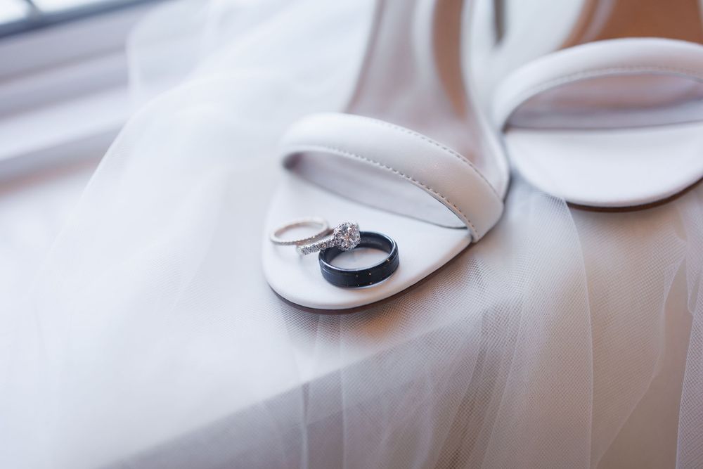 Wedding rings photographed on white bridal shoes with soft natural lighting.