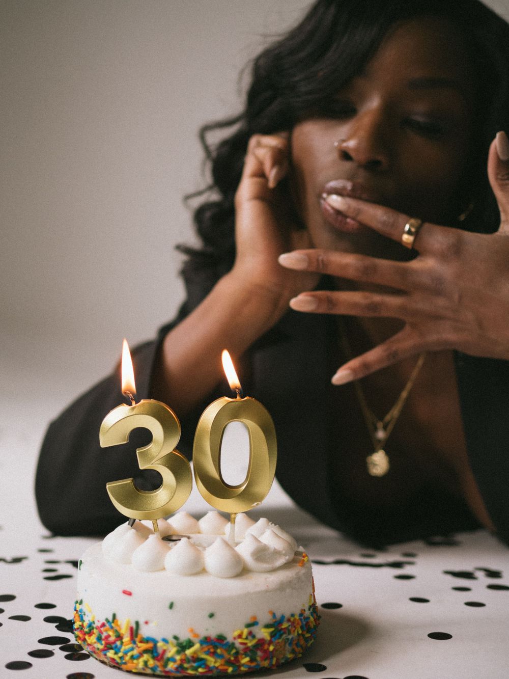 Birthday celebration photo with lit number 30 candles on decorated white cake.