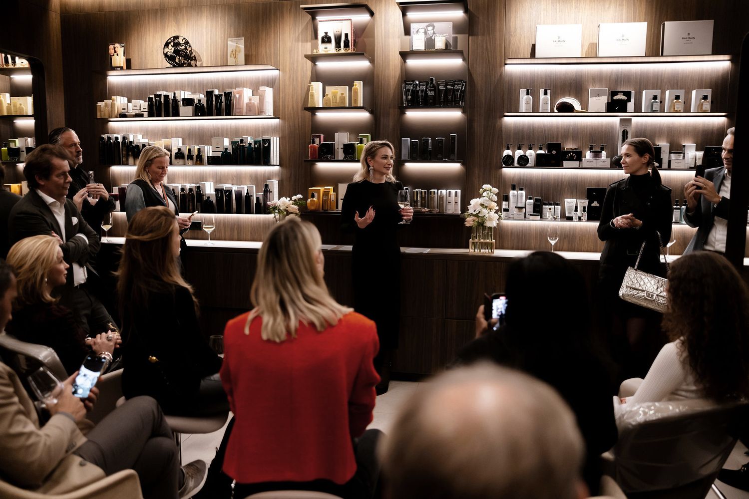 Customers attend a presentation in a retail store with shelves of products displayed behind them.