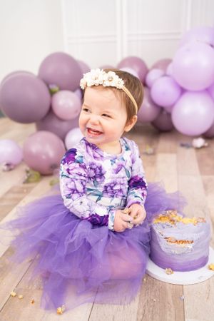 First birthday cake smash session with purple tulle dress and balloon decorations.