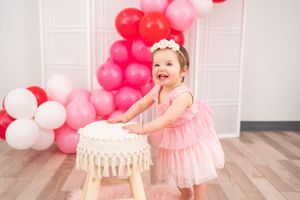 Pink and white balloon arch decorating a room with hardwood floors.