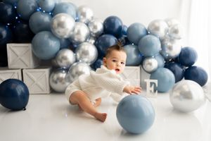 Navy blue and silver balloon arch installation with white backdrop.