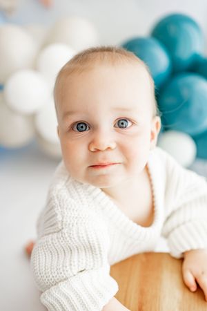 A closeup sequence of a baby in white knit clothing against a soft background with turquoise accents.