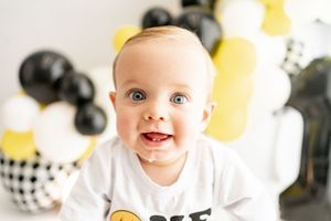 Modern birthday party decor with black and yellow balloons arranged against a white background.
