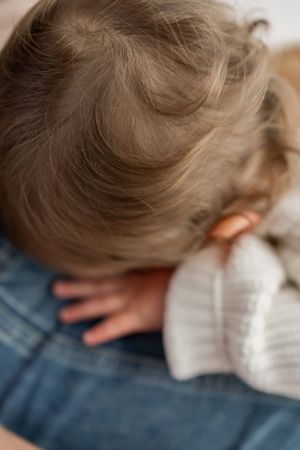 Close-up detail shot of soft brown hair against denim and white knit textures.