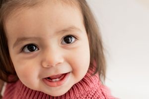 Adorable baby smiling and laughing in a sequence of five connected photos showing joy and happiness.