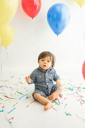 Birthday celebration setup with colorful balloons and confetti on white background.