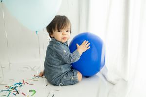 Blue balloon and confetti scattered on white studio floor.
