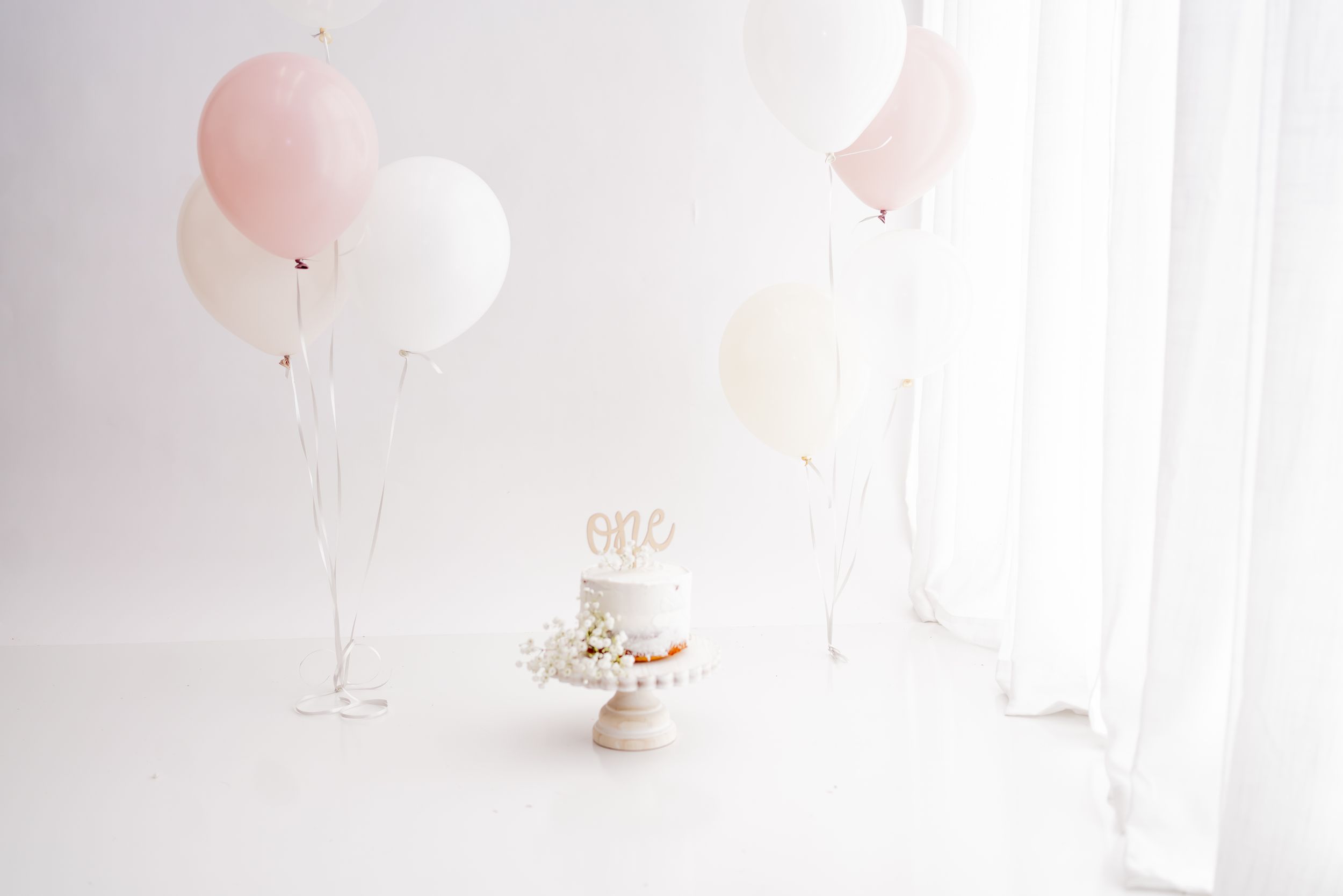 Pink and white balloons add a romantic touch to a bright, dreamy white interior space setting.