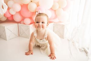 Pink and white balloons create a dreamy backdrop for a first birthday party celebration.