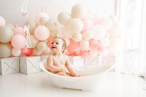 Sweet baby photoshoot setup with pink and white balloons creating a dreamy backdrop in natural light.