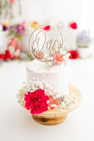 Romantic wedding place card holders with gold wire accents, red carnations, and dried baby's breath on white surface.