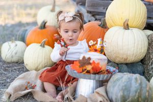 Festive fall scene with large pumpkins and rustic metal milk can decorated with autumn leaves.