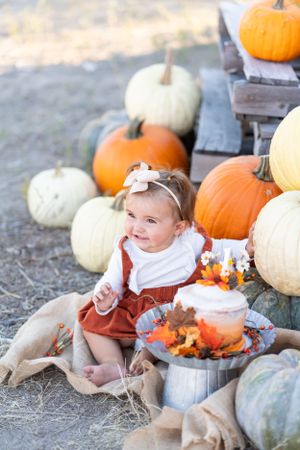 Fall themed celebration setup with pumpkins and festive cake display outdoors.