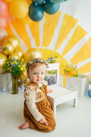 Charming photo setup with yellow sunburst background, balloons, and floral arrangements.