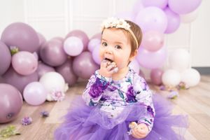 Purple and white balloon backdrop with tulle dress and party decorations.