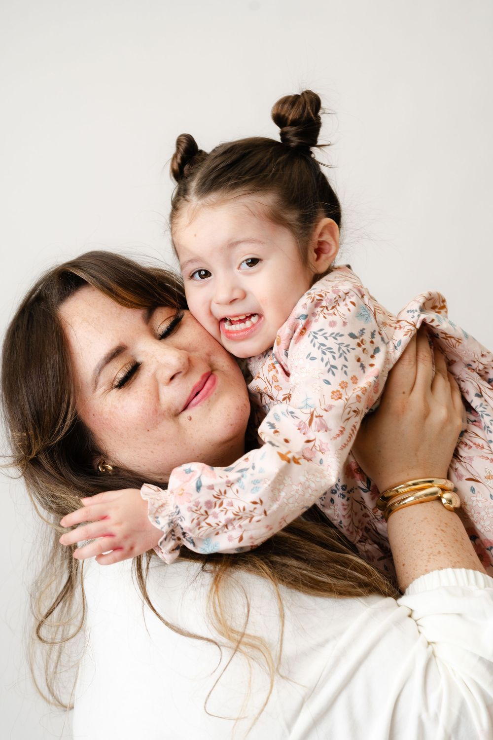 Sweet moment of parent and child embracing and sharing laugther together against white background.