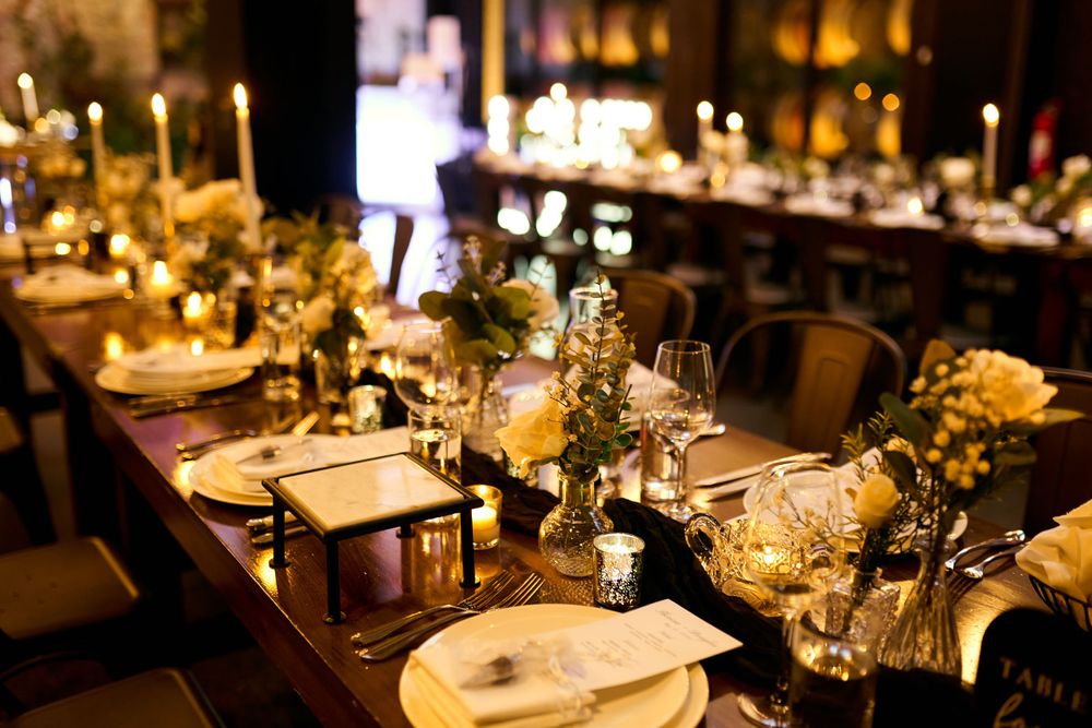 Elegant wedding reception tables set with glowing candlelight and sophisticated place settings.