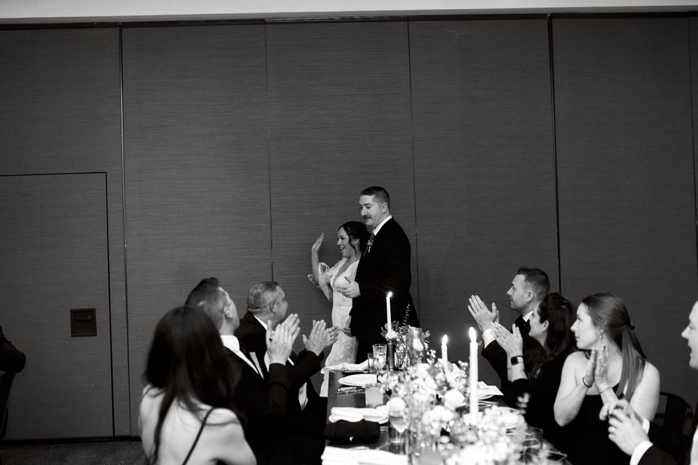 Black and white panoramic view of wedding reception guests enjoying dinner.