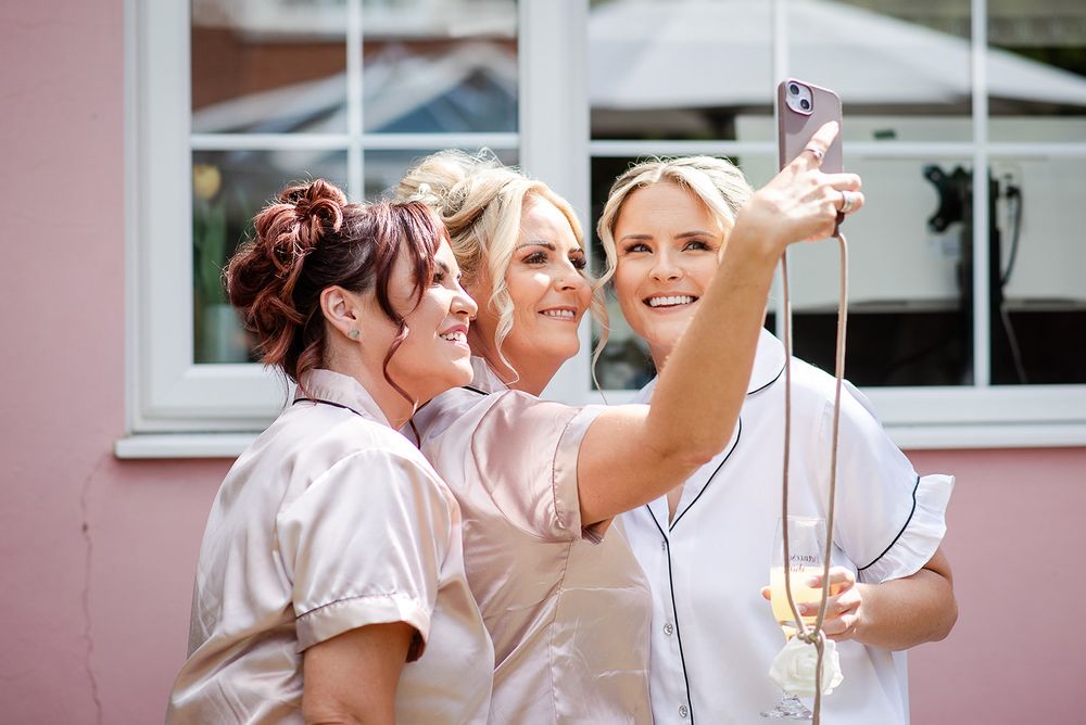 Group taking selfie while wearing matching robes outdoors.
