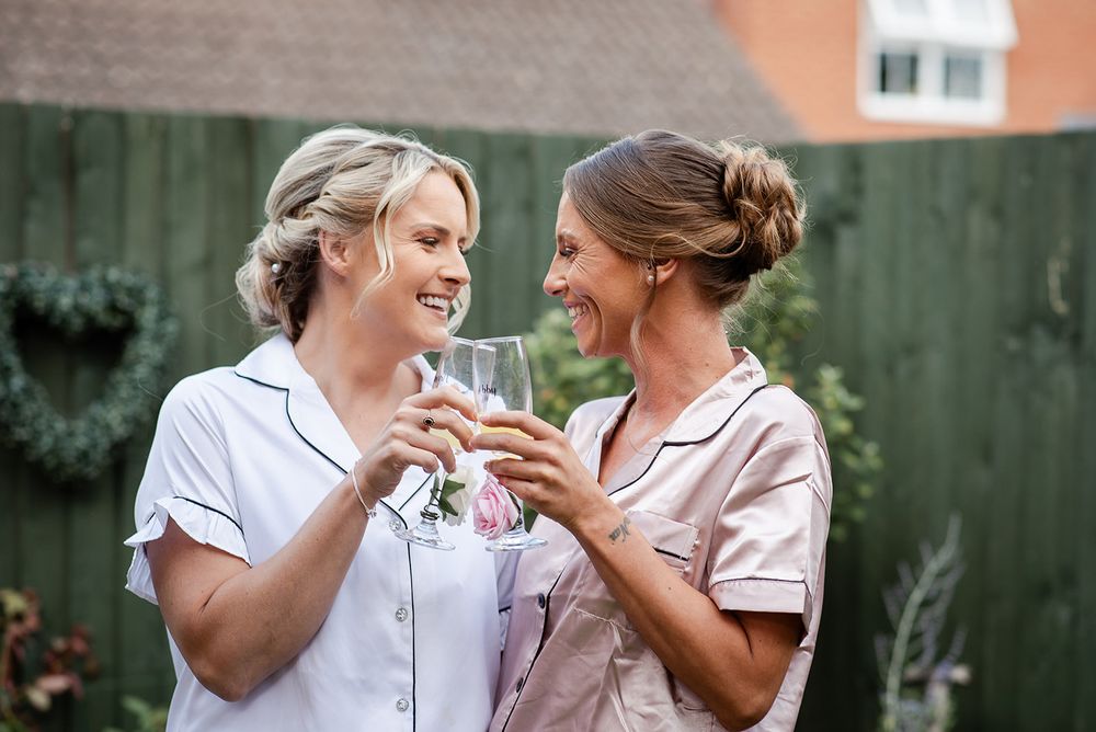 Two people in matching pajamas toasting with champagne in garden.