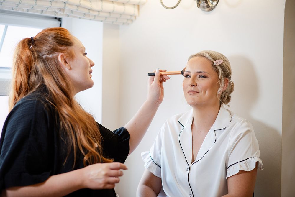 Makeup artist carefully applies eye makeup during bridal preparations.