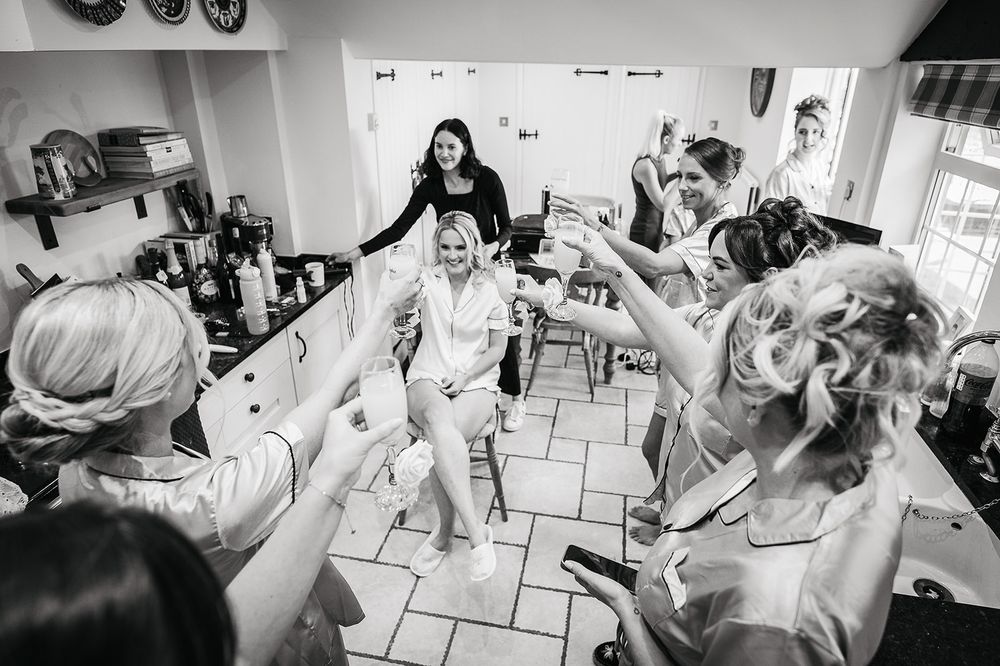Black and white photo of wedding party celebrating in a kitchen.