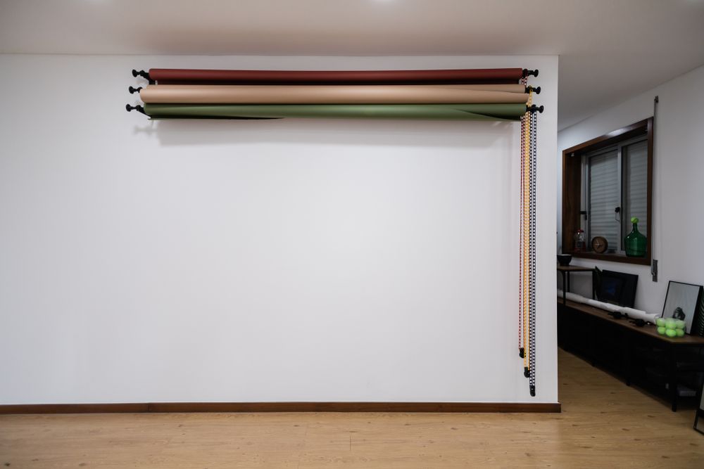 Modern interior with white walls and colored paper roll storage system mounted overhead.