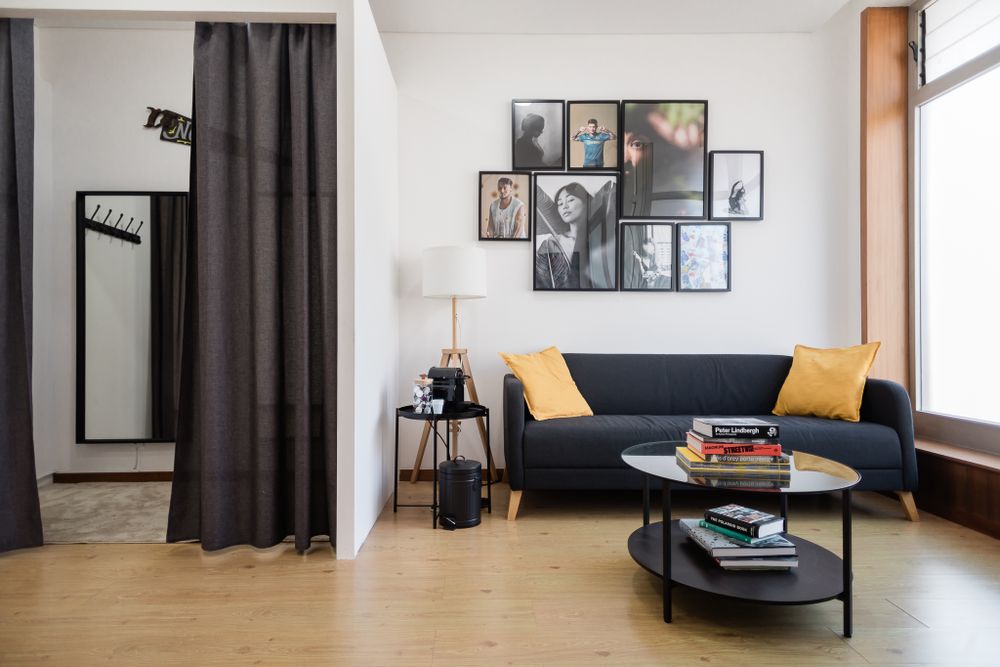Modern living room with dark sofa, yellow pillows, gallery wall and floor-length curtains.