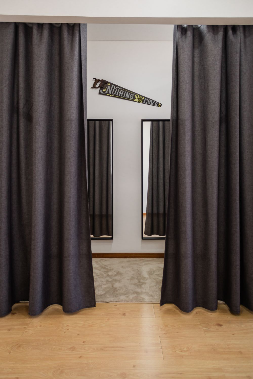 Dressing room entrance with dark curtains, mirrors, and a sign displayed on white walls.