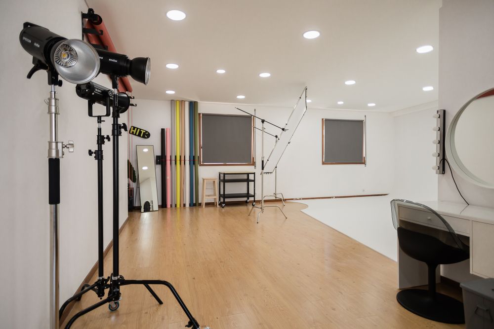 Professional photography studio setup with multiple lights and equipment on wooden floor.