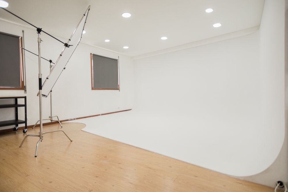 Empty photography studio with curved white backdrop and professional lighting equipment.