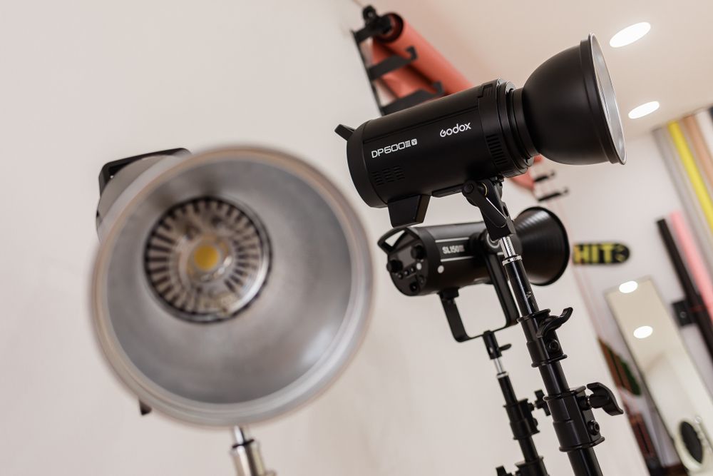 Professional studio lighting equipment with black spotlight and silver reflector mounted on stands.