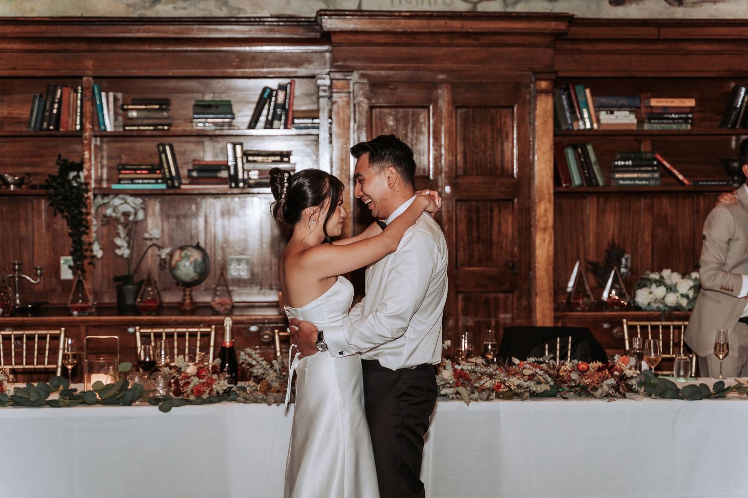 A romantic first dance between newlyweds in an elegant wood-paneled library setting.