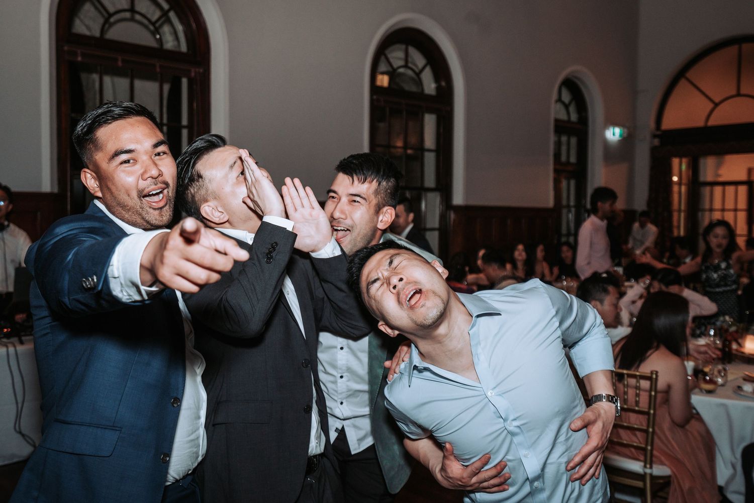 Group of wedding guests posing playfully for photos during reception celebrations.
