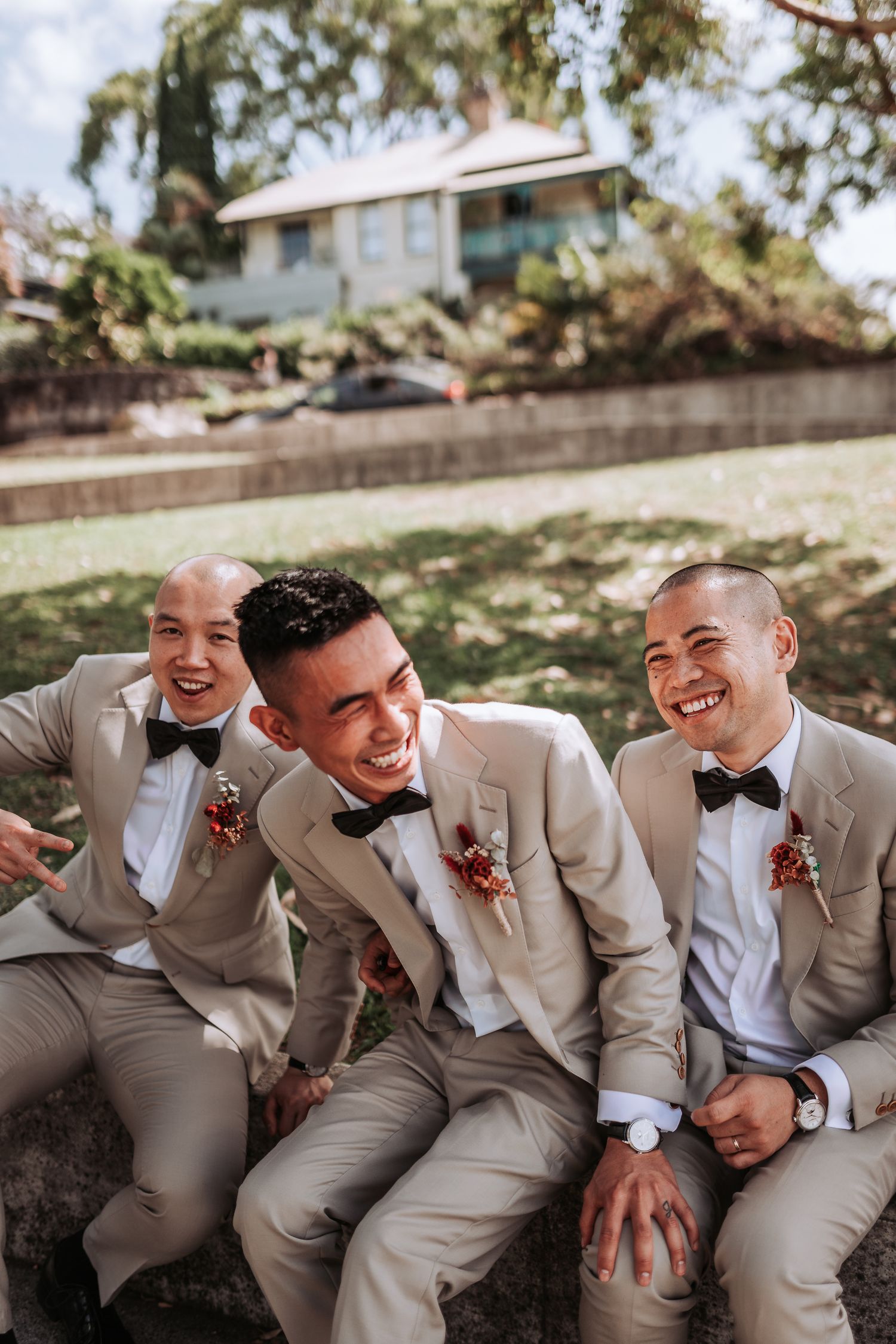 Wedding party relaxes on stone wall during outdoor photo session.