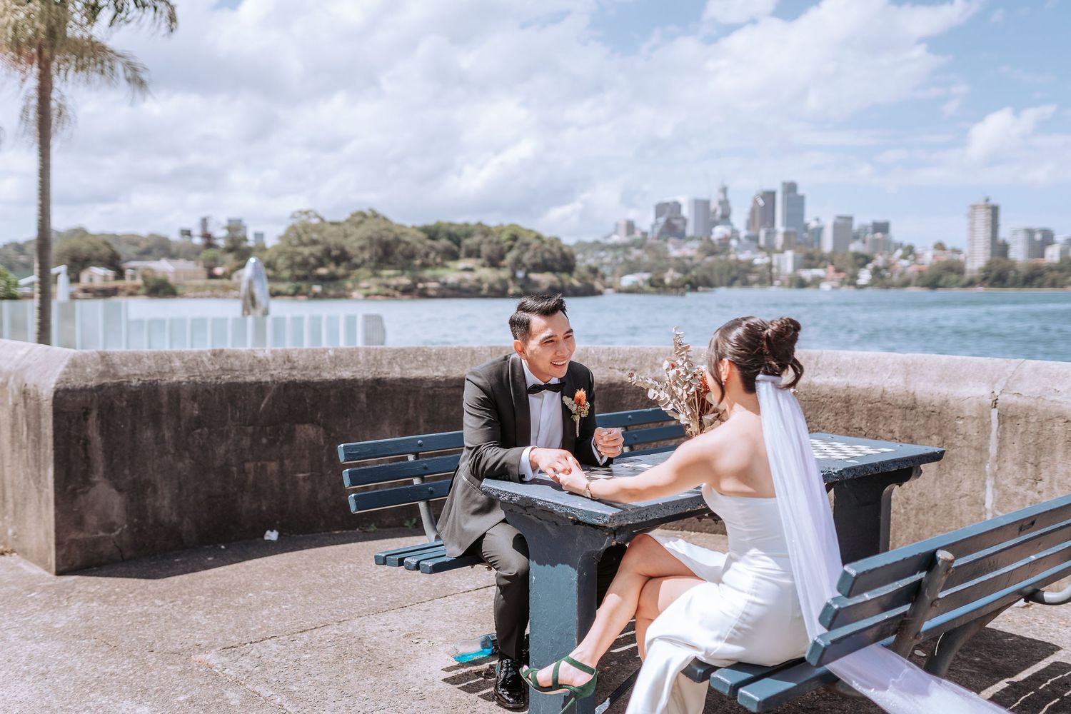Couple shares romantic moment on bench overlooking Sydney Harbour.