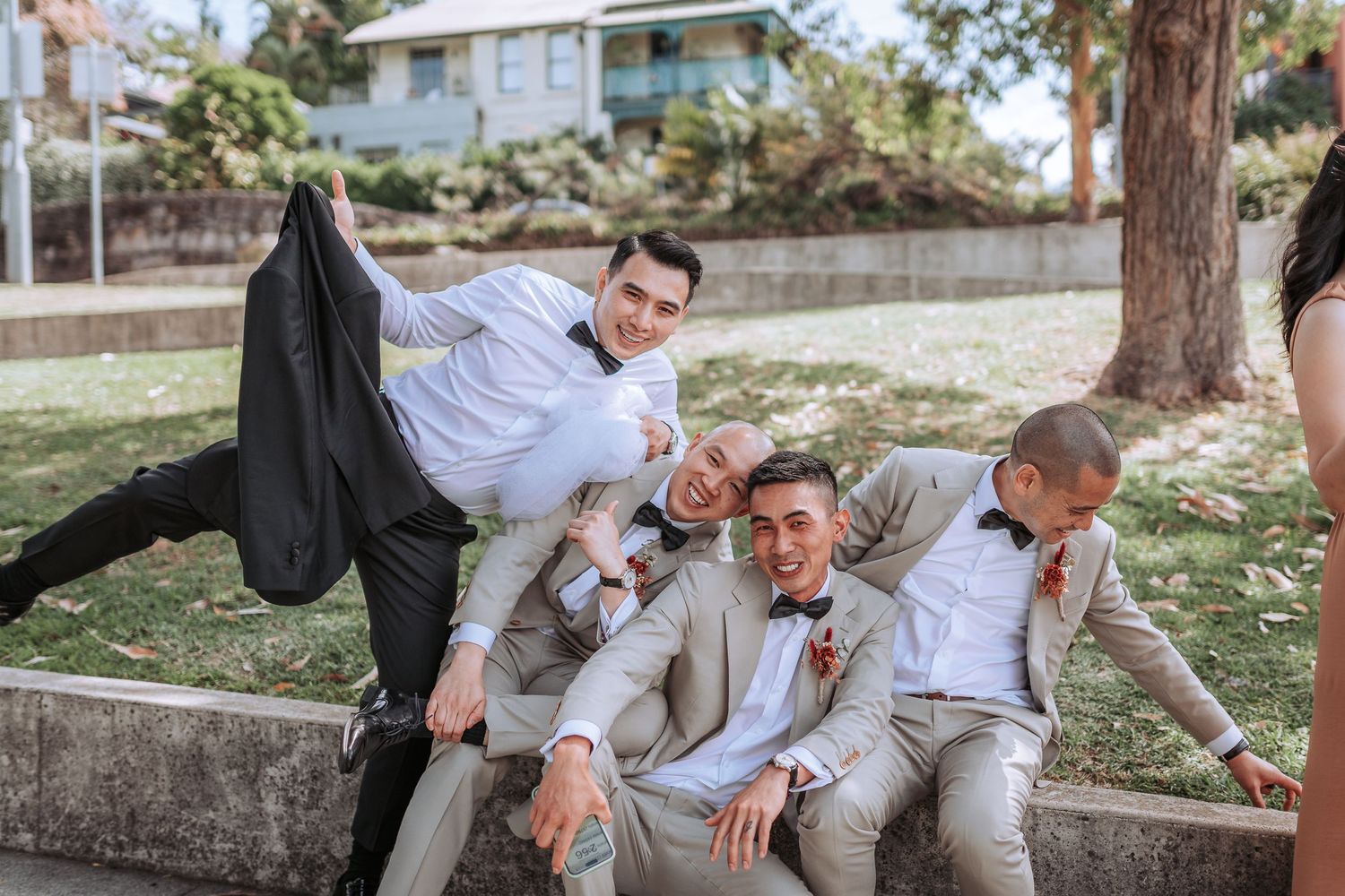 Wedding party in gray suits posing playfully on outdoor stone steps.