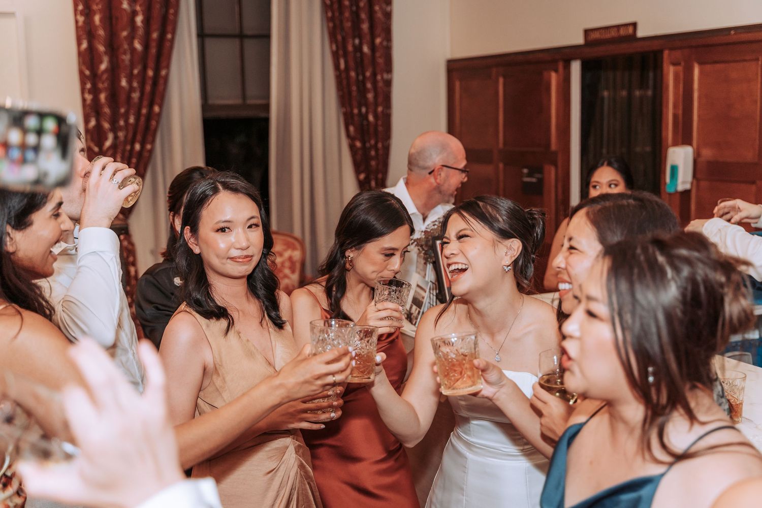 Wedding celebration with guests in formal attire toasting and cheering.