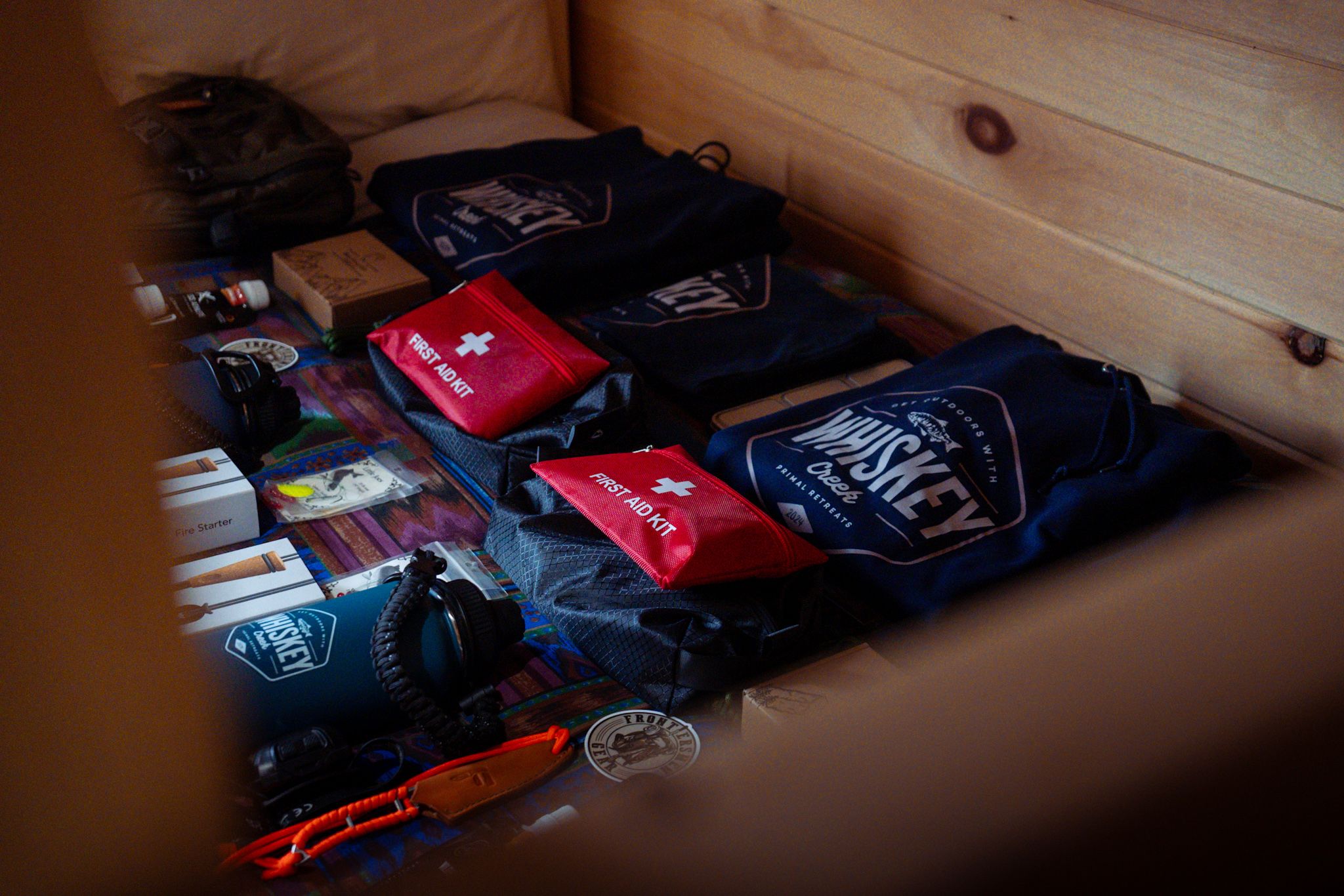 Collection of folded clothing and sports merchandise with red and navy colors arranged in wooden storage space.