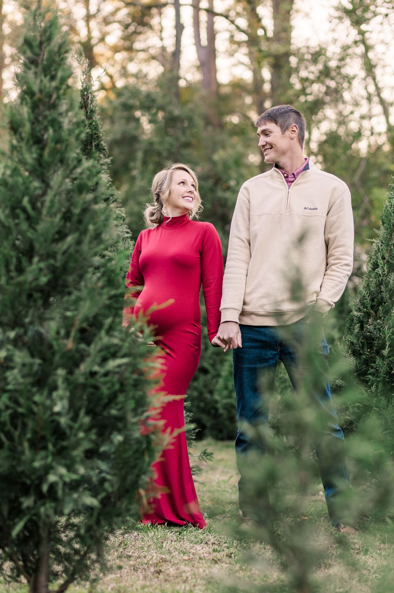 A couple shares a joyful moment while walking through a Christmas tree farm.