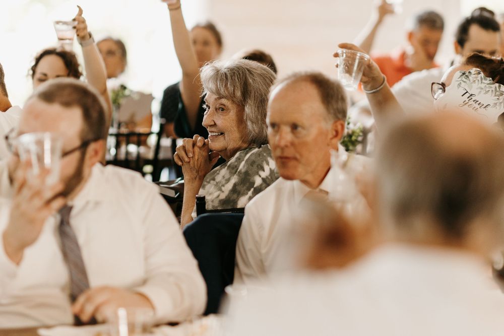 Wedding guests raise glasses in a joyful toast during a reception celebration.