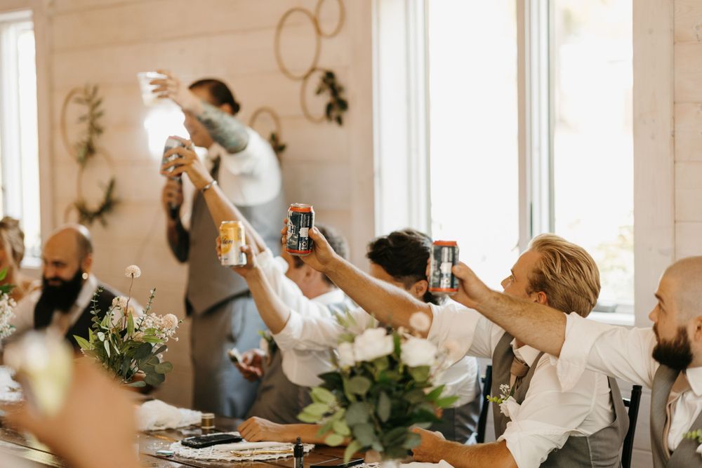 Wedding guests raise drinks in a celebratory toast at rustic barn reception.