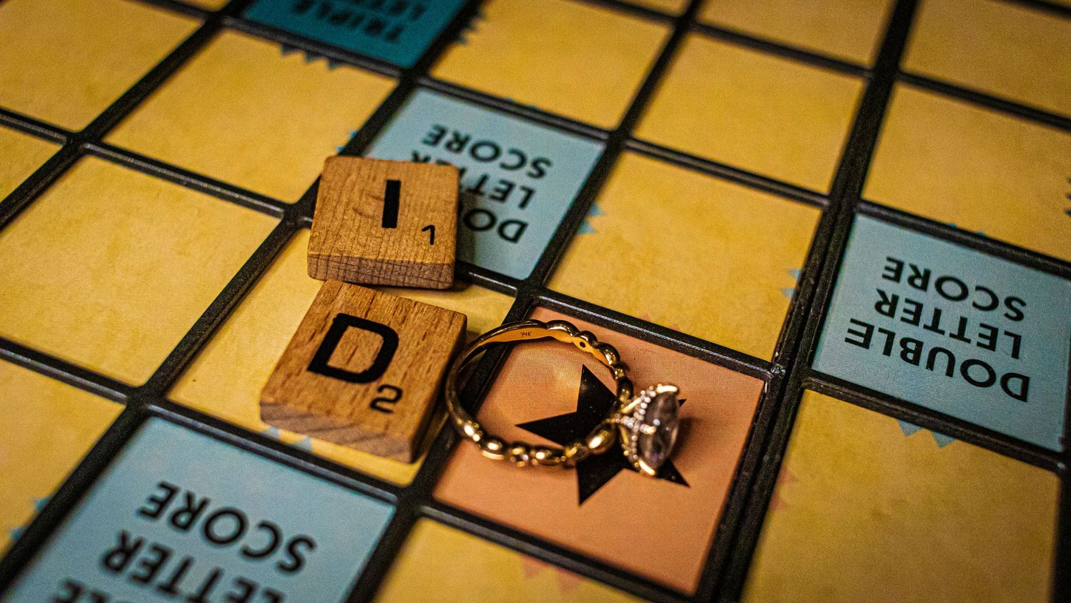 Engagement ring displayed with wooden scrabble tiles on vintage game board.