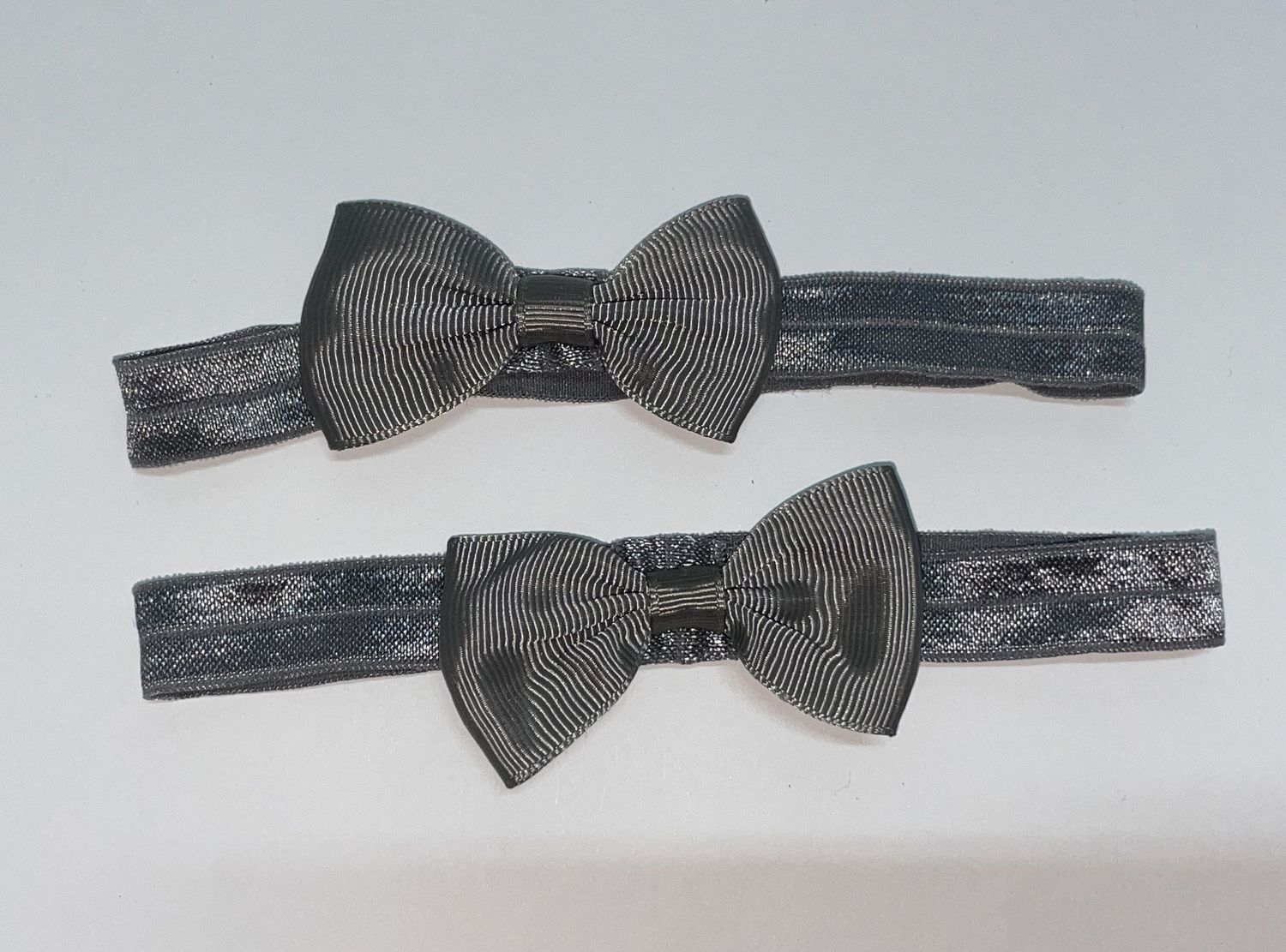 Set of gray bow ties arranged on elastic headbands.