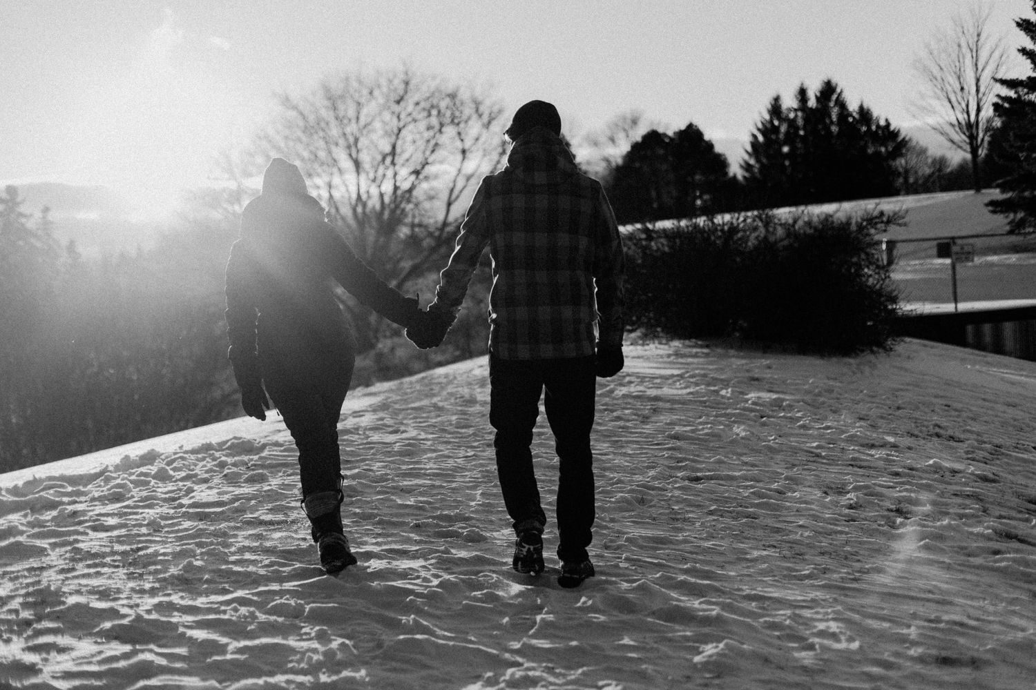 Couple holding hands and walking on the hill covered with snow durint sunset in New Market