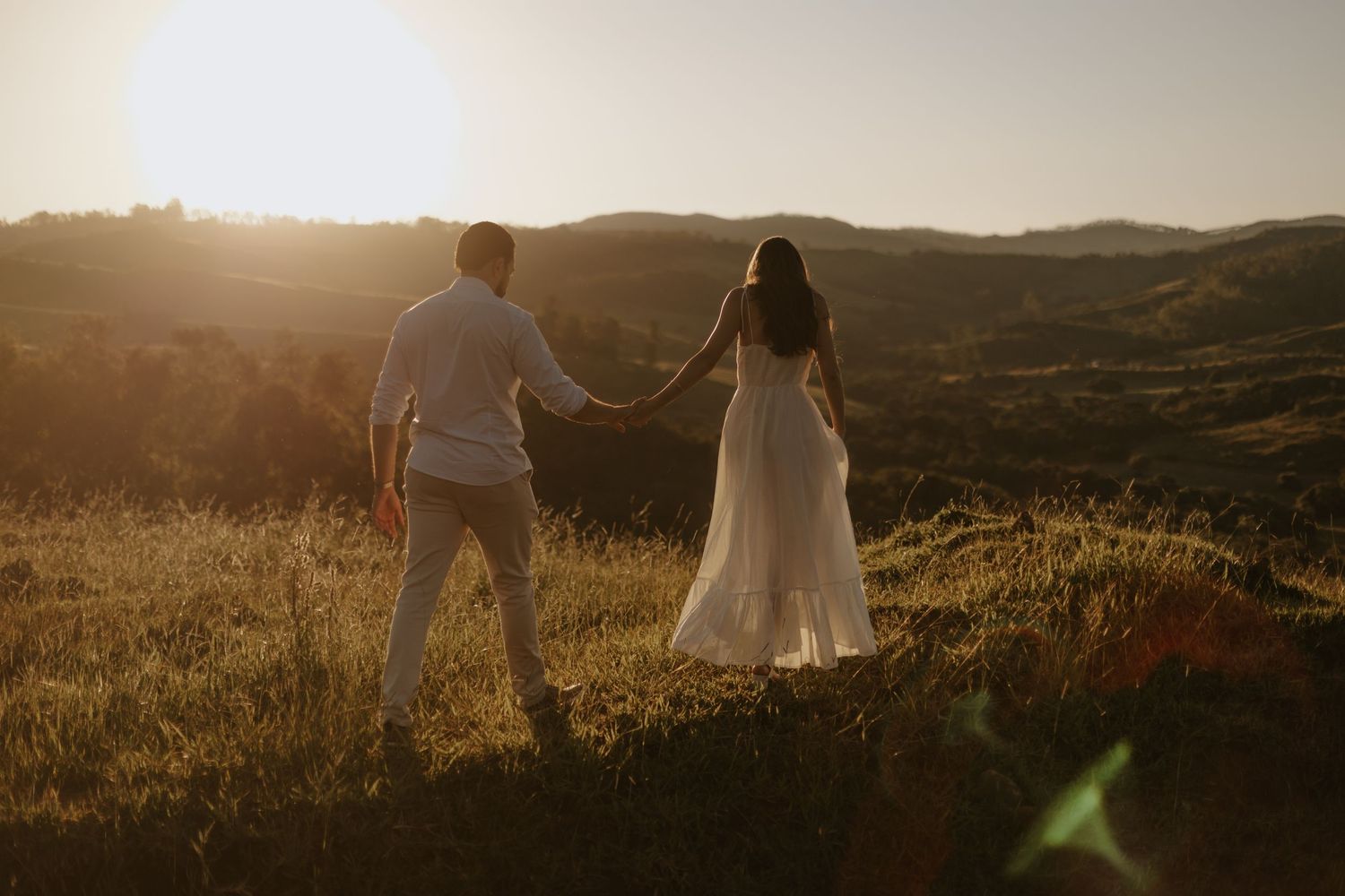 Couple holding hands and walking on the hill covered with snow durint sunset